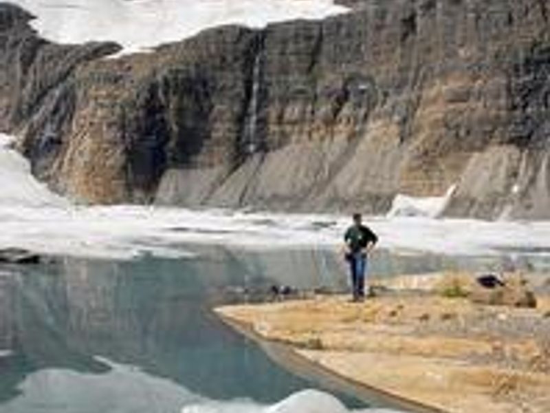 A man views rock cliffs above an alpine lake