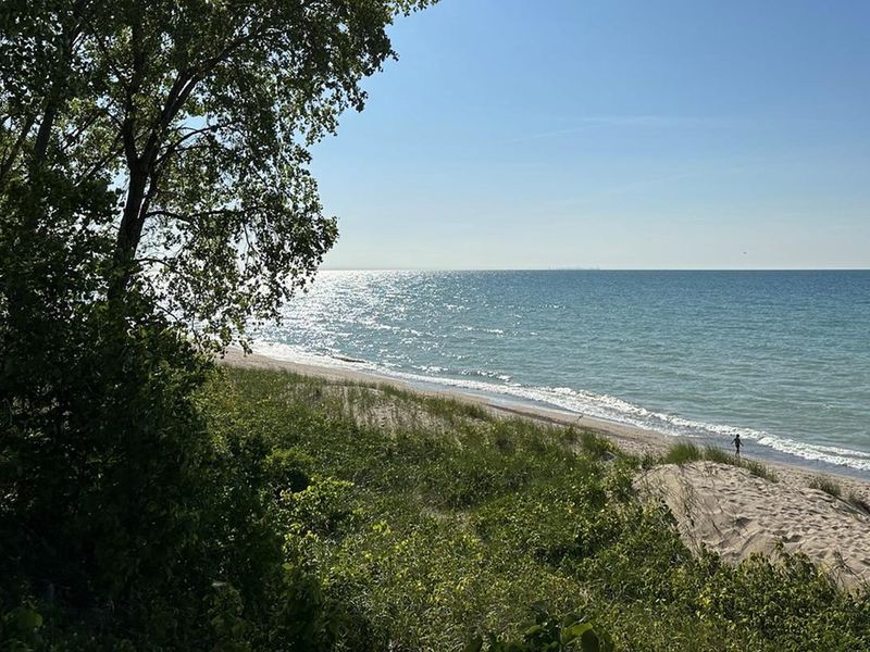 A visitor walks in the sunshine along the shore at Dunbar Beach