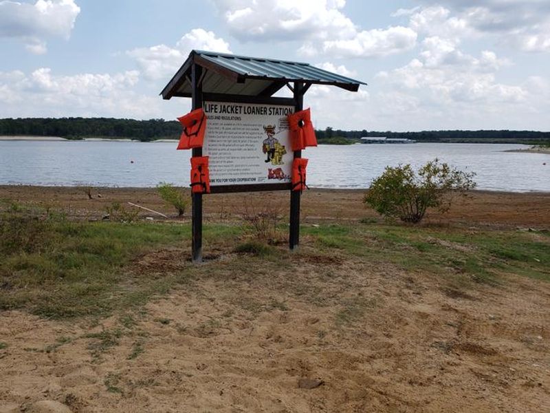 Lilly Road offers a swim beach with loaner lifejacket station, nearby playground, picnic tables, and restrooms. 